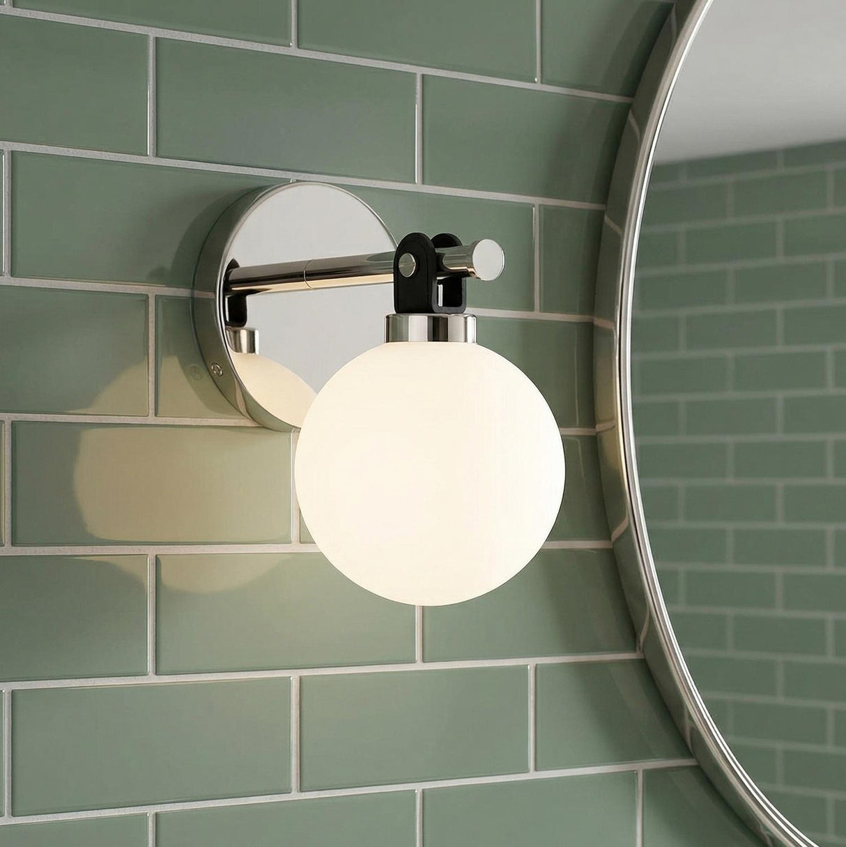 Bryce Vanity Wall Sconce, Polished Nickel globe wall sconce in a Modern Bathroom with sage green subway tile and a round mirror.