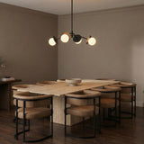 Matte Black globe design Chandelier in a Modern Dining Room with a travertine stone table and tan leather chairs.