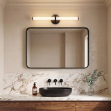 A modern bathroom featuring the Ellie LED Vanity Light in matte black and glass mounted above a black-framed mirror, white marble backsplash, and a vessel sink.