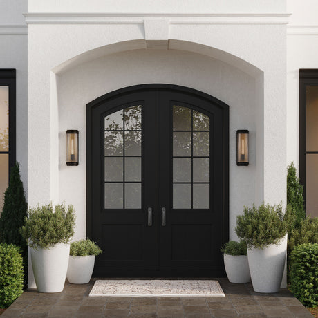 Two Bristol Outdoor 15" Wall Lights with Reeded Glass flanking a set of black arched front doors, with white stucco and green potted plants