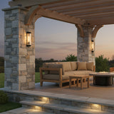 Bristol Outdoor Wall Light, Matte Black with Brass Accents - Outdoor patio with stone pillars, wooden pergola, sectional sofa, fire pit, and step lighting.