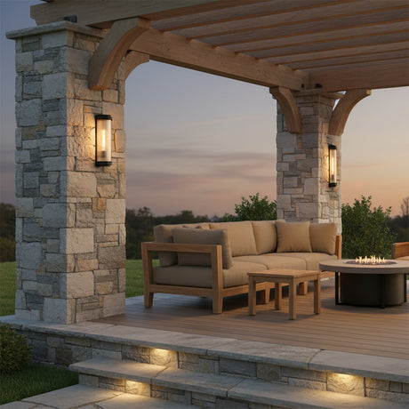 Bristol Outdoor Wall Light, Matte Black with Brass Accents - Outdoor patio with stone pillars, wooden pergola, sectional sofa, fire pit, and step lighting.