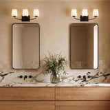 A transitional bathroom with two matte black Blake 3 Light Vanity fixtures featuring frosted glass shades above rectangular mirrors, a marble countertop, and oak cabinetry.