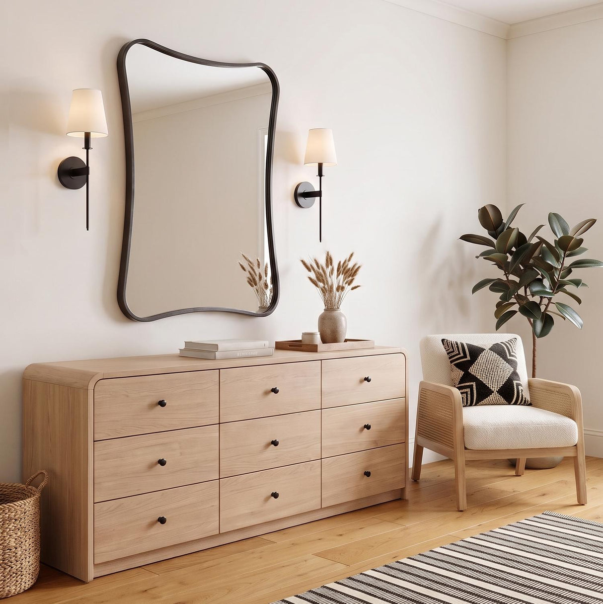 A modern bedroom featuring two Taylor Wall Sconces in matte black with white linen shades flanking a curved mirror above a light oak wood dresser on hardwood floors.
