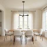 Matte Black geometric Chandelier in a Modern Dining Room with a light wood dining table and cream upholstered chairs.