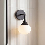 Talia Wall Sconce, Matte Black globe Wall Sconce in a Modern Bathroom with vertical fluted tile and a black framed mirror.