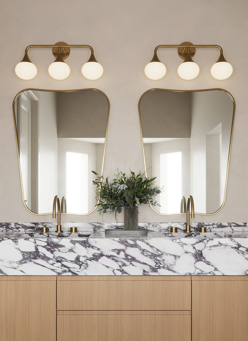 Two Talia 24" wide LED Vanity Lights in Aged Brass are shown in a modern bathroom above two FA 33 style mirrors, with beige plaster walls.