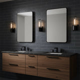 Lea Wall Sconce, Matte Black - Two wall sconces flanking mirrors over a wooden vanity with black countertops.