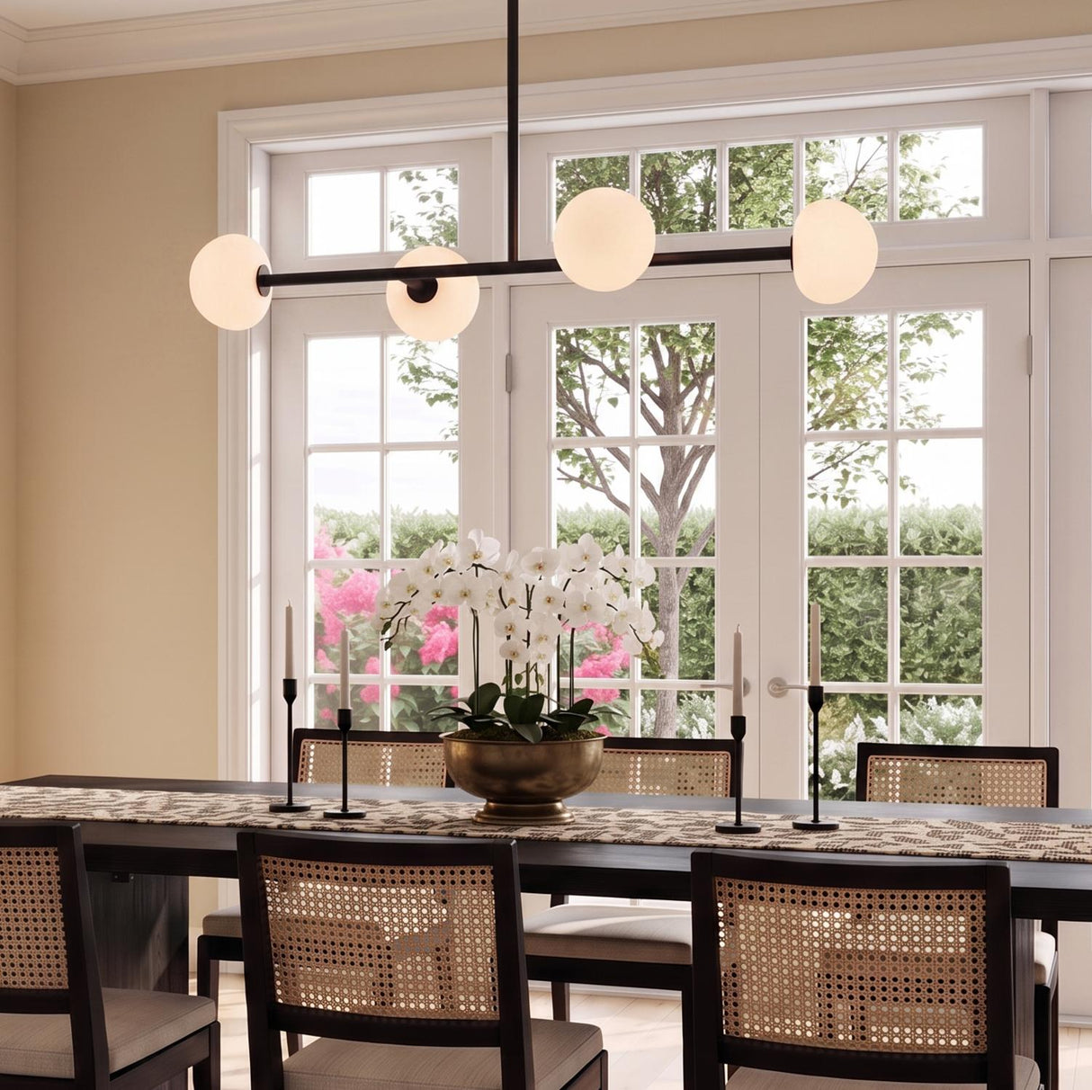 A transitional dining room with the Vince 4 Light Linear Pendant in matte black with frosted globe shades suspended over a dark wood table and cane chairs.