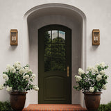 Brighton Outdoor 14" Wall Light, Burnished Brass and Clear Glass with Cream Sleeves, flanking an arched entryway with dark green door