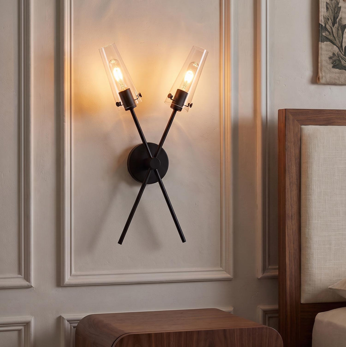 A transitional bedroom featuring a matte black Mason 2 Light Wall Sconce with clear glass cylinders mounted inside wall molding beside a walnut wood headboard.