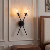 A transitional bedroom featuring a matte black Mason 2 Light Wall Sconce with clear glass cylinders mounted inside wall molding beside a walnut wood headboard.