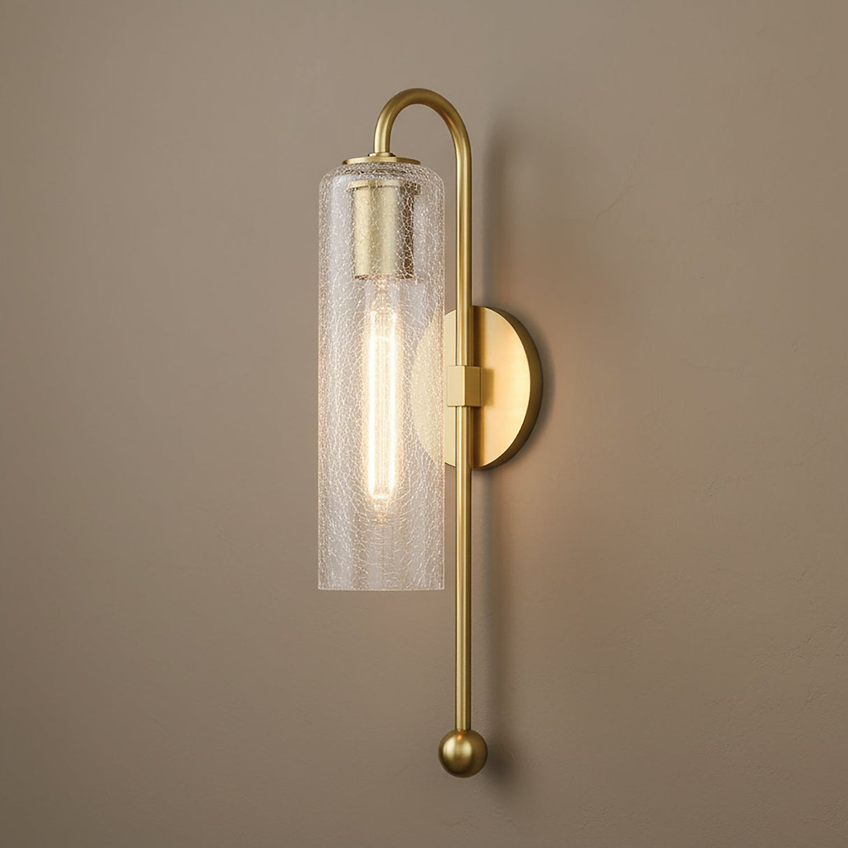 Dessie 19" Wall Sconce in Aged Brass with clear crackled glass shade shown on a taupe brown wall.