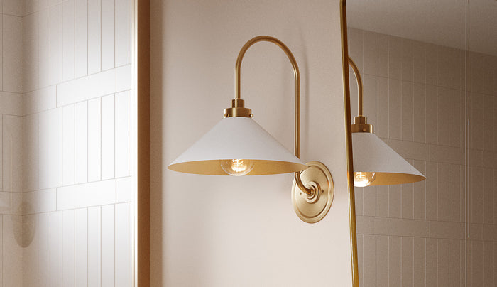 Alma Metal Wall Sconce shown in white and aged brass finish in a modern bathroom.