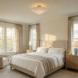 White linen and Brass scalloped semi-flush mount in a Transitional Bedroom with an upholstered bed and wood nightstands.
