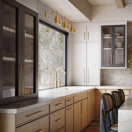 Three Faye Adjustable Aged Brass Metal Wall Sconces, with Gooseneck Curved Arms in Aged Brass are shown above a large window and kitchen sink in a modern home.