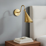 Faye Adjustable Metal Wall Sconce, Aged Brass - Brass sconce beside bedside table and upholstered headboard