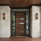 Everett Forged Iron Black geometric outdoor wall light in a Modern Outdoor entryway with a wood door and glass panels.