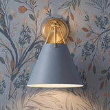 A transitional foyer features the Bowie Wall Sconce, French Blue and Brass with a brushed brass backplate mounted against botanical floral wallpaper.