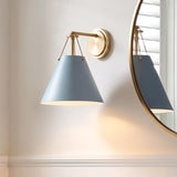 A transitional bathroom features a Bowie Wall Sconce, French Blue and Brass, installed beside a round brass mirror above white wainscoting.