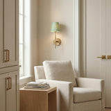 Sage Green and Brass geometric wall sconce in a Transitional Living Room with a linen armchair and wood table.