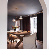 A transitional dining room with the Banks 2 Shade Linear Pendant 42", White and Brass in brushed brass and linen over a wood table with velvet curtains.