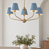 A transitional dining room featuring the Banks 5 Light Chandelier 28", French Blue and Brass hanging above a wood dining table with a ceramic vase.