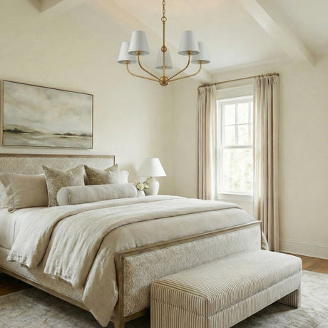 White and Brass geometric chandelier in a Transitional Bedroom with an upholstered bed and striped bench.