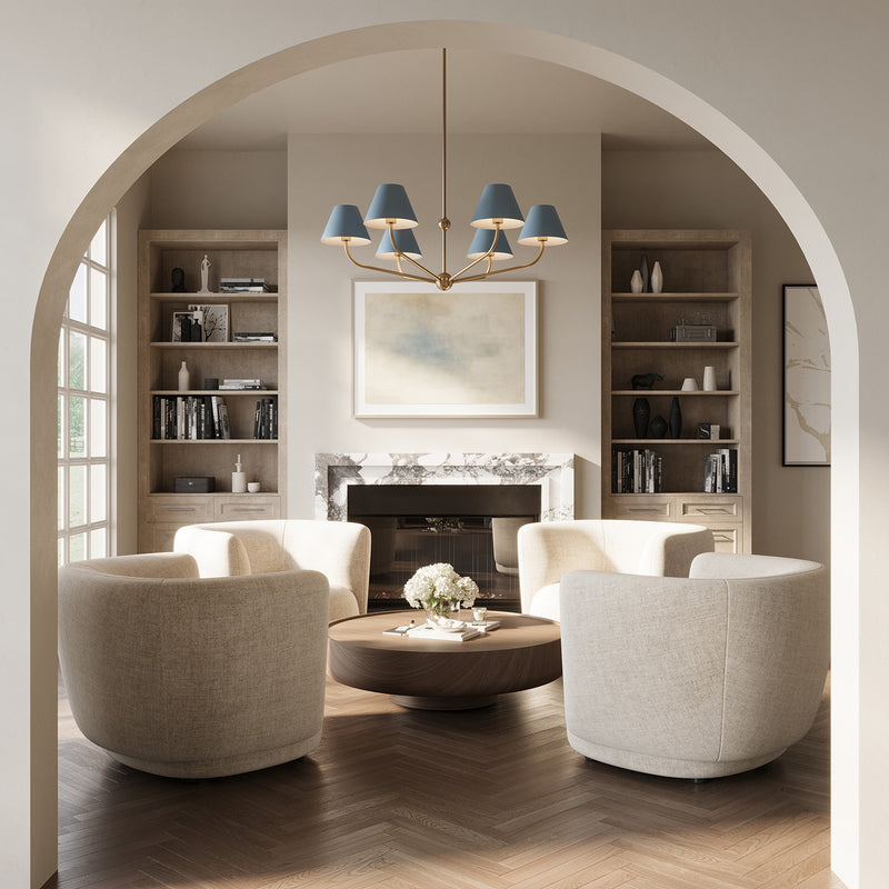 Banks French Blue Chandelier, with brass accents, 40" wide and with six conical shades, is hung in a contemporary living room with an arched entry, seating area with cream swivel chairs, and herringbone wood floors. 