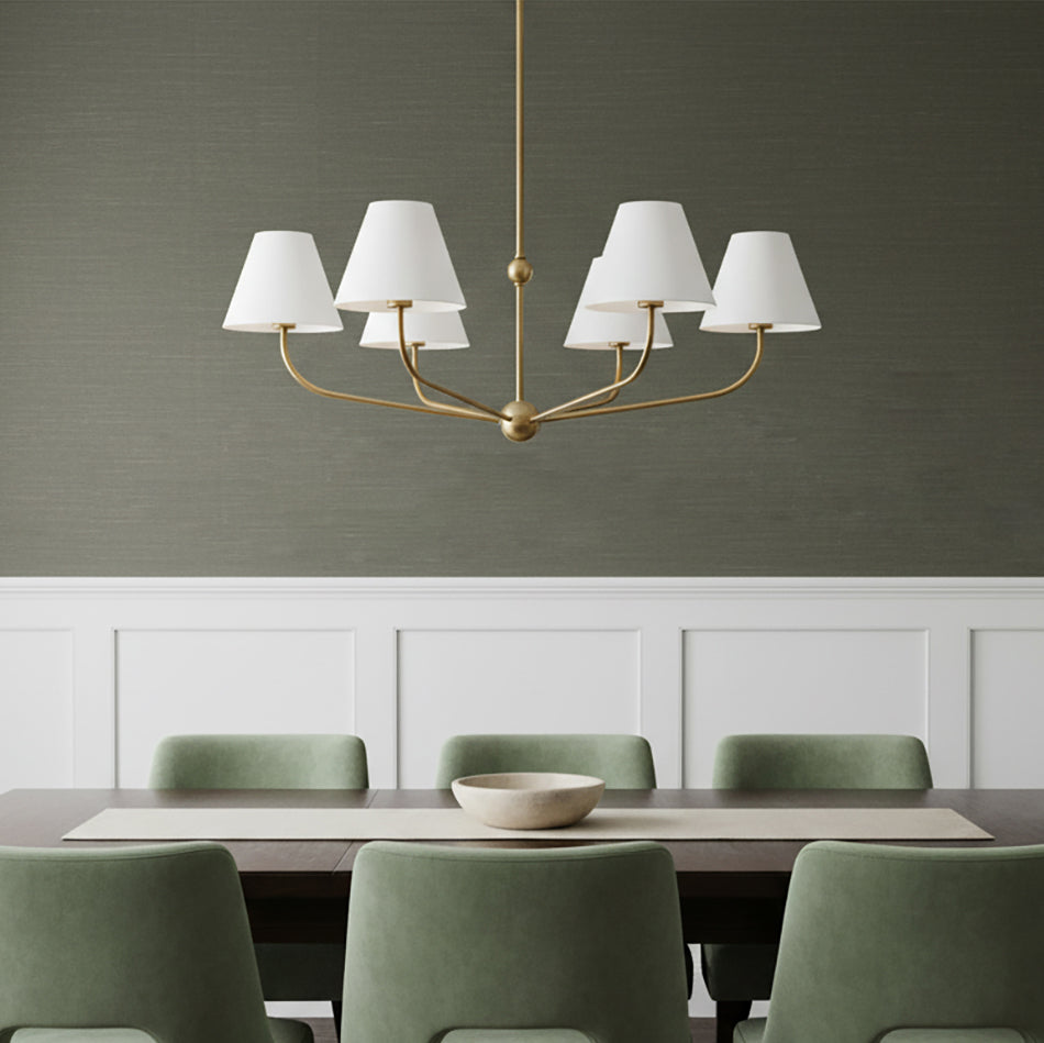 Banks 6 Light Chandelier 40, White and Brass - A brass chandelier with white shades hangs over a dark wood dining table with green chairs.