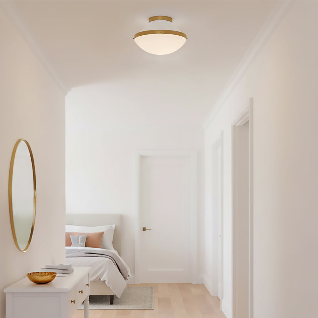 Blair Flush Mount 12, White and Brass - Flush mount ceiling light with brass accents and a white diffuser illuminates a modern hallway with a bed and dresser visible in the background.