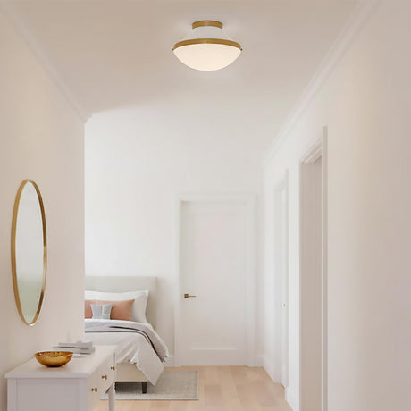 Blair Flush Mount 12, White and Brass - Flush mount ceiling light with brass accents and a white diffuser illuminates a modern hallway with a bed and dresser visible in the background.