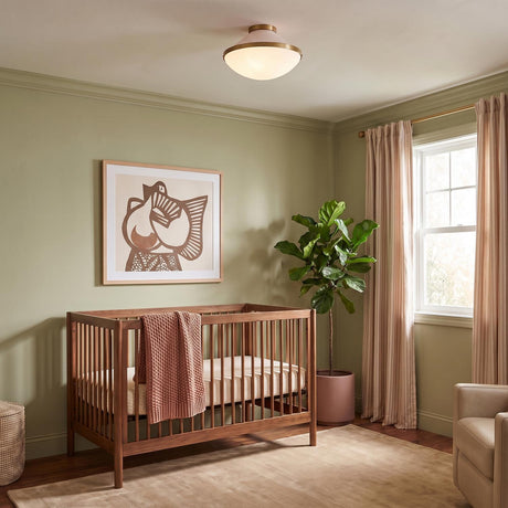 A mid-century modern bedroom with the Blair Flush Mount 16", Rose Quartz and Brass on the ceiling above a walnut wood crib and olive green walls.