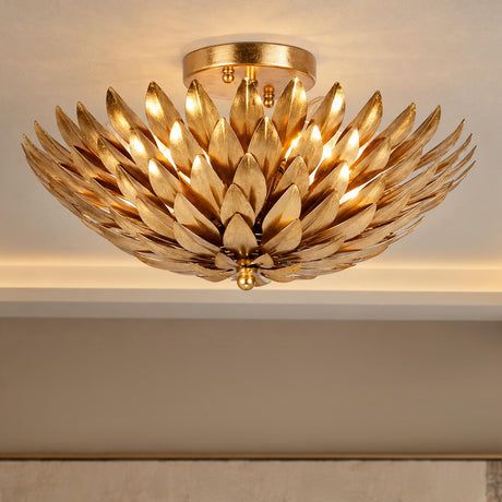 A transitional living room featuring an antique gold semi-flush mount fixture with layered metal leaf petals glowing against an off-white ceiling.