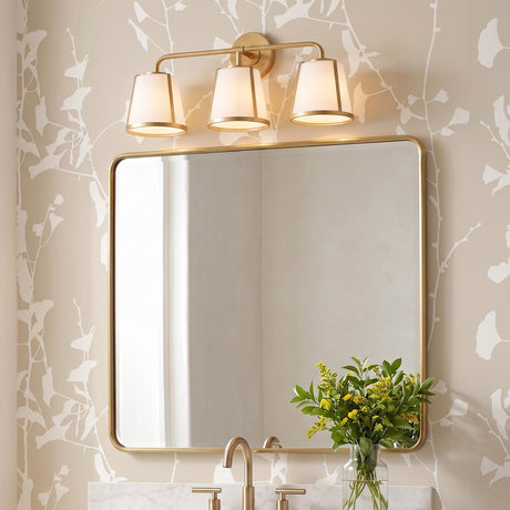 A transitional bathroom featuring the Hoyt 3 Light Vanity, Antique Gold with Opal Glass installed above a rounded brass mirror and marble vanity countertop.