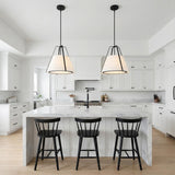 A modern kitchen featuring two Hoyt Pendant 20", Black with matte black frames and white linen shades hanging over a white marble waterfall island.