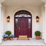 A Mediterranean home entry with two matte black Ellington Outdoor Wall Light fixtures flanking a burgundy front door on beige stucco with blue hydrangeas and boxwood.