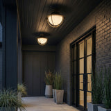 Tobin Outdoor Flush Mount, Black and Brass geometric globe flush mount in a Modern Outdoor with a dark brick wall and concrete planters.