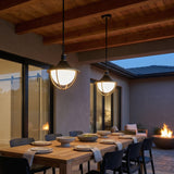 Tobin Outdoor Pendant Light 16", Black and Textured Gold globe Pendant in a Modern Outdoor with a rustic wood dining table and fire pit.