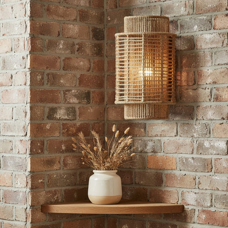 Sellah 16" tall wall sconce in natural jute is shown on an exposed brick wall.