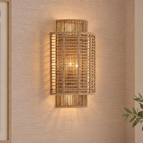 A coastal living room features the Sellah Wall Sconce, Jute and Satin Sand, mounted on a beige textured grasscloth wall beside a light wood frame.
