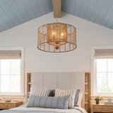 A coastal bedroom with the Sellah 4 Light Pendant 25", Jute and Satin Sand hanging along the ceiling center above a beige headboard and vaulted blue shiplap ceiling.