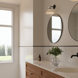 Cori Wall Sconce, Matte Black and Milk Glass, shown above an oval bathroom vanity mirror.