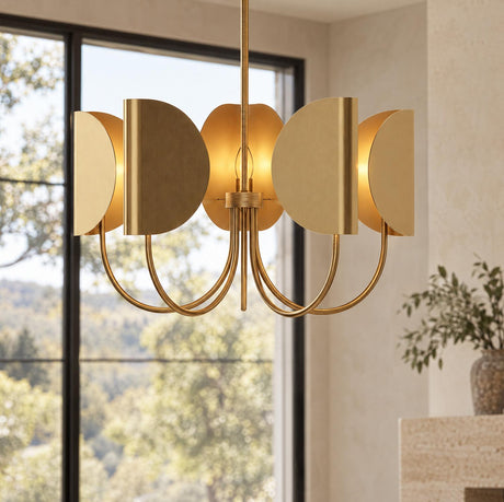 A contemporary living room showcases the Nico 5 Light Chandelier 32", Antique Brass positioned beside a large black-framed window with scenic outdoor views.