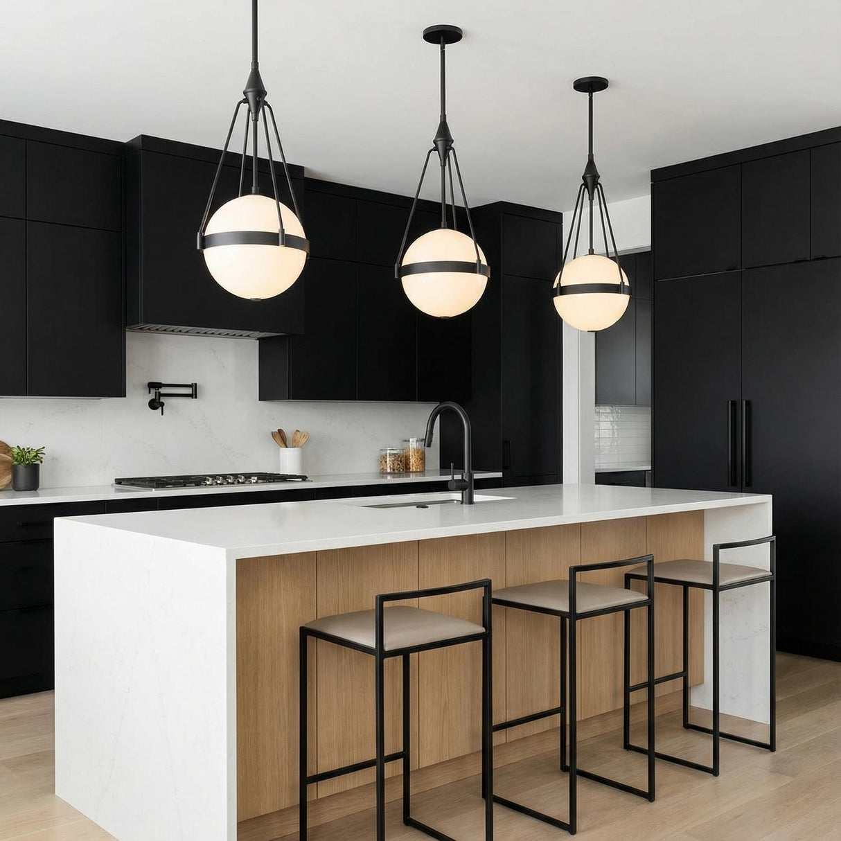 A minimalist kitchen features three Darcy Medium Pendant 14" Matte Black and Milk Glass fixtures suspended over a white waterfall island and black flat-panel cabinets.