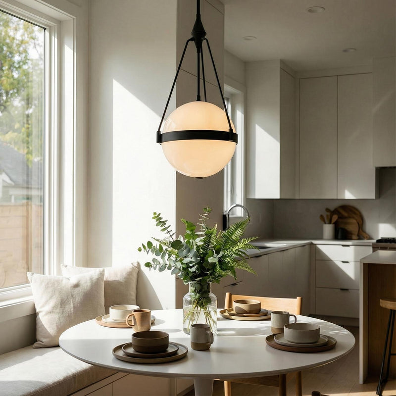 A modern kitchen breakfast nook featuring the Darcy Medium Pendant 14 inch in matte black and milk glass over a white circular table with neutral cabinetry.