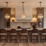 A modern farmhouse kitchen with three Darcy Large Pendants in brushed brass and water glass over a marble-topped wood island and five arched wooden barstools.