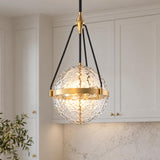 A transitional kitchen features the Darcy Large Pendant 18", Brushed Brass and Water Glass hanging in front of off-white shaker cabinetry and a white marble backsplash.