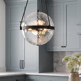 A transitional kitchen with a Darcy Large Pendant 18", Matte Black and Water Glass suspended over a white marble countertop and blue-gray shaker cabinets.