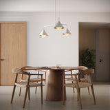 Juno 38" wide three light chandelier in white finish above a round modern dining table with four chairs.